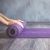 Eine Frau rollt eine lila Yogamatte aus