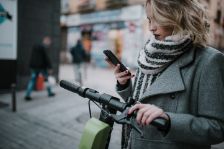 Junge Frau fährt mit dem E-Scooter durch die Stadt.