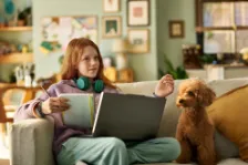 Ein junges Mädchen sitzt auf dem Sofa und erkundigt sich mit ihrem Computer über eine Berufsunfähigkeitsversicherung für Schüler.