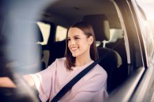 Ein junge Teenagerin sitzt im Auto und lernt Autofahren.