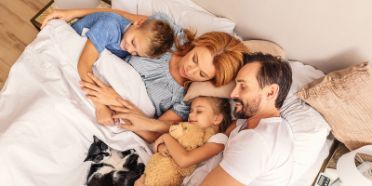 Eine Familie liegt im Bett und schläft friedlich.