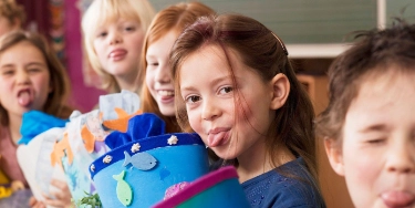 Kinder mit Schultüte in der Hand strecken die Zunge raus.