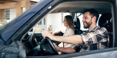 Mann und Frau fahren in einem blauen Auto.