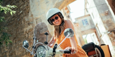 Eine Frau hat Spaß beim Fahren ihres Mopeds, dem eine gültige Haftpflicht zu Grunde liegt.