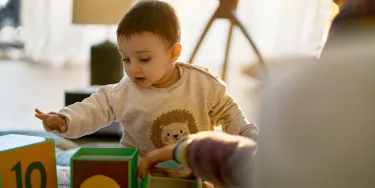 Ein Kind sitzt auf dem Boden uns spielt mit Spielzeug.