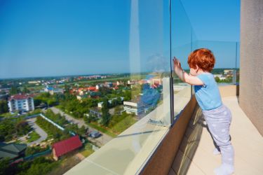 Ein kleiner Junge genießt die Aussicht auf die Stadt von der Dachterrasse eines mehrstöckigen Gebäudes
