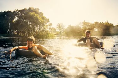 Vater und Sohn im Fluss auf Schwimmreifen.