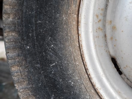 Abgenutzter Autoreifen neben glänzendem Metallfelgenrand, zeigt Verschleiß und Reifenprofilverschleiß