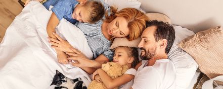 Eine Familie liegt im Bett und schläft friedlich.