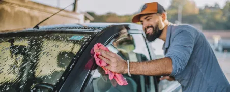 Mann wäscht Auto per Hand.