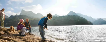 Eine Familie steht an einem See in den Bergen, als Symbol für finanzielle Absicherung.