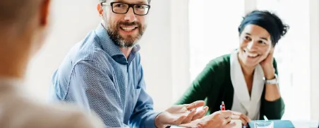 Drei Beamte unterhalten sich in einem Meeting und üben ihre berufliche Tätigkeit aus.