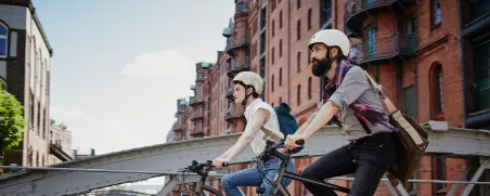 Zwei Personen fahren mit e-bike durch Stadt.