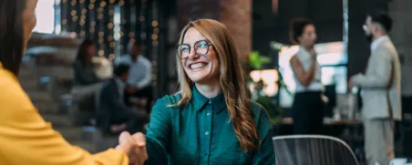 Eine Frau schüttelt nach einem erfolgreichen Bewerbungsgespräch die Hand der Arbeitgeberin.