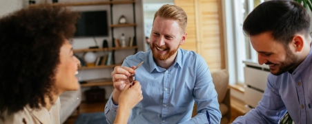 Mieter und Vermieter freuen sich bei der Schlüsselübergabe.