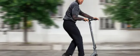 Junger Mann fährt auf seinem E-Scooter und beide sind gut versichert.