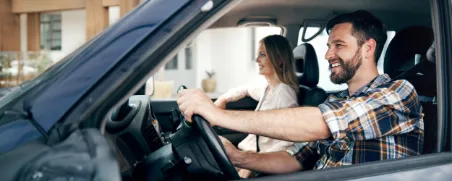 Mann und Frau fahren in einem blauen Auto.