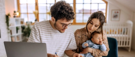 Eine junge Familie informiert sich über mögliche finanzielle Unterstützung für sie und ihr Baby. 