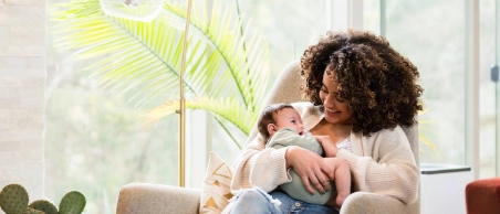 Eine junge Mutter hält ihr Baby im Arm und genießt die erste Zeit nach der Geburt mit finanzieller Unterstützung durch Mutterschaftsgeld.