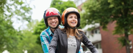 Eine Frau und ein Mann auf einem Moped haben sich über die Unterschiede von Rollern und anderen Kleinkrafträdern informiert.