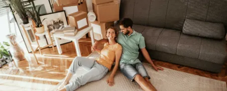 Ein junges Paar ist umgezogen und sitzt in der neuen Wohnung.