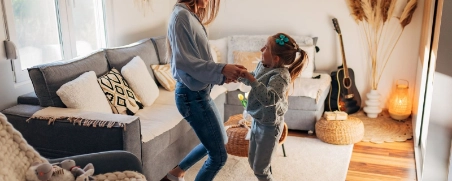 Mutter und Tochter springen gemeinsam im Wohnzimmer.