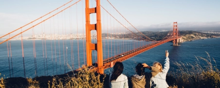 3 junge Leute genießen die Aussicht auf die Golden Gate Bridge bei Ihrem Urlaub in den USA.