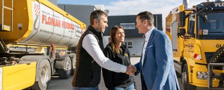 Zwei Mitarbeitende einer Logistikfirma schütteln einem R+V Generalagenten die Hand