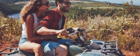Eine Frau und ein Mann können die Fahrt auf ihrem Quad genießen, weil sie durch eine Versicherung gut abgesichert sind.
