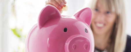 Rosa Sparschwein mit Münzen im Hintergrund, Konzept für Ersparnisse und Finanzplanung