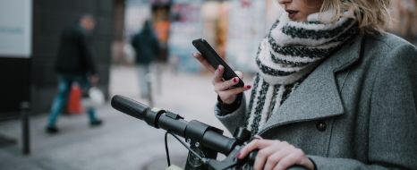 Junge Frau fährt mit dem E-Scooter durch die Stadt.