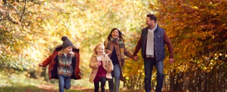 Eine Familie geht gemeinsam im herbstlichen Wald spazieren.