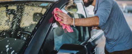 Mann wäscht Auto per Hand.