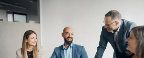 Vier Kolleginnen und Kollegen unterhalten sich in einem Büro vor einem Notebook.