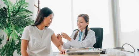 Eine Ärztin impft eine Frau gegen Gürtelrose.