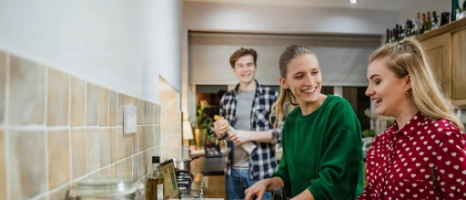 Junge Mitbewohner einer Wohngemeinschaft kochen gemeinsam.