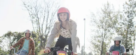3 junge Leute fahren bei schönem Wetter auf ihren Mofas.