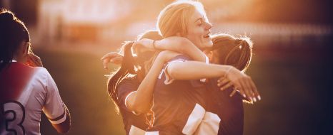 Junge Frauen spielen Fussball und freuen sich