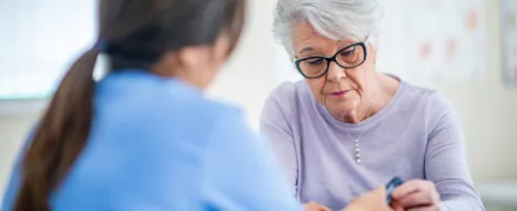 Beratungssituation mit Pflegerin und weisshaariger Frau zum Thema Pflegehilfsmittel