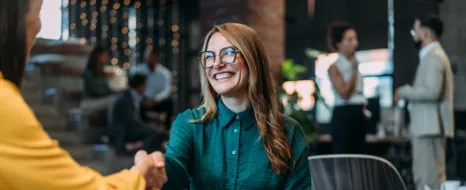 Eine Frau schüttelt nach einem erfolgreichen Bewerbungsgespräch die Hand der Arbeitgeberin.