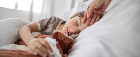 Eine Kind ist im Urlaub krank geworden. Es liegt im Bett und schläft. 