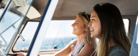 Zwei Frauen fahren mit dem Auto an der Küste entlang.