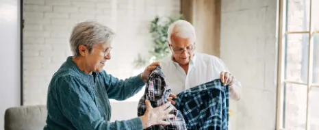 Senioriger Mann packt Kleidung in einen Koffer gemeinsam mit seiner Frau