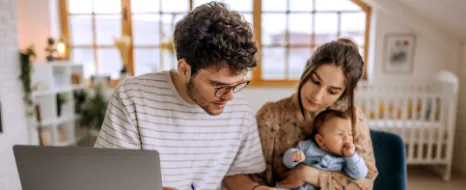 Eine junge Familie informiert sich über mögliche finanzielle Unterstützung für sie und ihr Baby. 