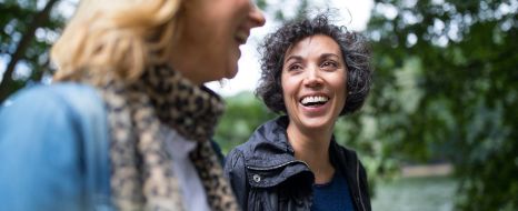 Frauen mittleren Alters lachen zusammen.