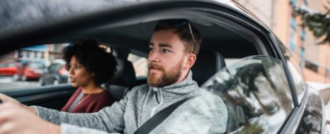 Mann und Frau fahren mit dem Auto durch die Stadt.