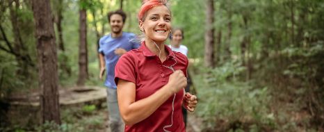 Mehrere Personen joggen durch einen Wald.