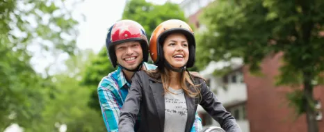 Eine Frau und ein Mann auf einem Moped haben sich über die Unterschiede von Rollern und anderen Kleinkrafträdern informiert.