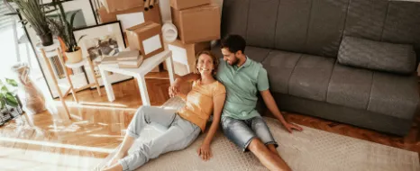 Ein junges Paar ist umgezogen und sitzt in der neuen Wohnung.