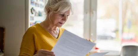 Eine pflegende Angehörige prüft Leistungen bei Pflegegrad 4 in einem schriftlichen Dokument.
